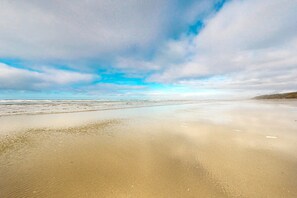 Ein Strand mit breitem Sandstrand und blauem Himmel.