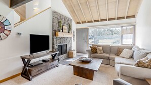 A living room with a TV, a fireplace, a sofa, and a coffee table. - Updated home golf course view, pool, & tennis - wood fireplace, grill, and deck (Sunriver)