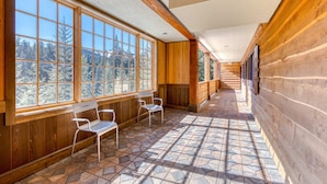 A corridor with large windows, wooden walls, and a tiled floor. - Luxury mountain home withshared pool & hot tub, patio, balcony views, & free WiFi (Government Camp)