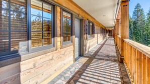 A long corridor with wooden walls and large windows, leading to a door marked '203'. - Luxury mountain home withshared pool & hot tub, patio, balcony views, & free WiFi (Government Camp)