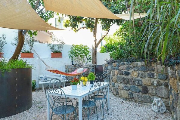 An outdoor patio with a table and chairs, surrounded by potted plants and a hammock. - Villa Trani - close to the beach (Ischia)