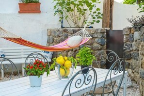 A white table with metal chairs, a hammock, potted plants, and a stone wall. - Villa Trani - close to the beach (Ischia)