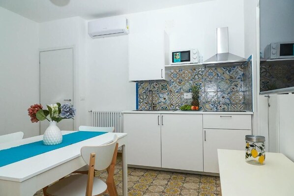 A compact kitchen with white cabinets, a microwave, and a tiled backsplash. - Villa Trani - close to the beach (Ischia)