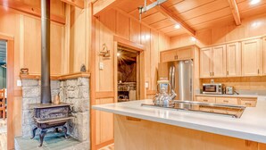 Un interior de madera con chimenea de piedra, refrigerador de acero inoxidable y microondas.