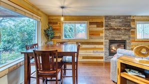 Ein Holzinterieur mit Esstisch, Stühlen, Kamin und einer Couch.