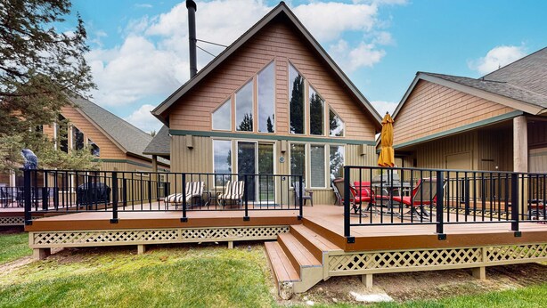 A two-story house with a deck, large windows, and a chimney.