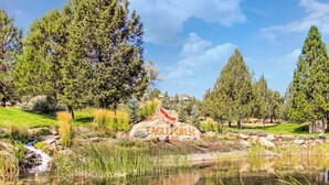 A serene landscape with a pond, trees, and a rock with 'EAGLE CREEST' inscribed.