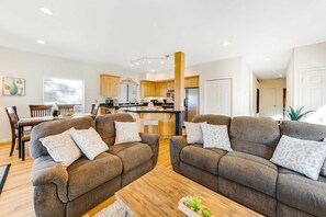 A modern living room with two sofas, a coffee table, and a dining area with chairs.