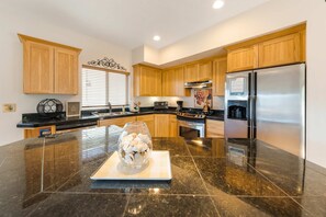 A modern kitchen with wooden cabinets, a stainless steel refrigerator, and a marble countertop.