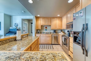 A kitchen with granite countertops, wooden cabinets, stainless steel appliances, and a built-in oven.