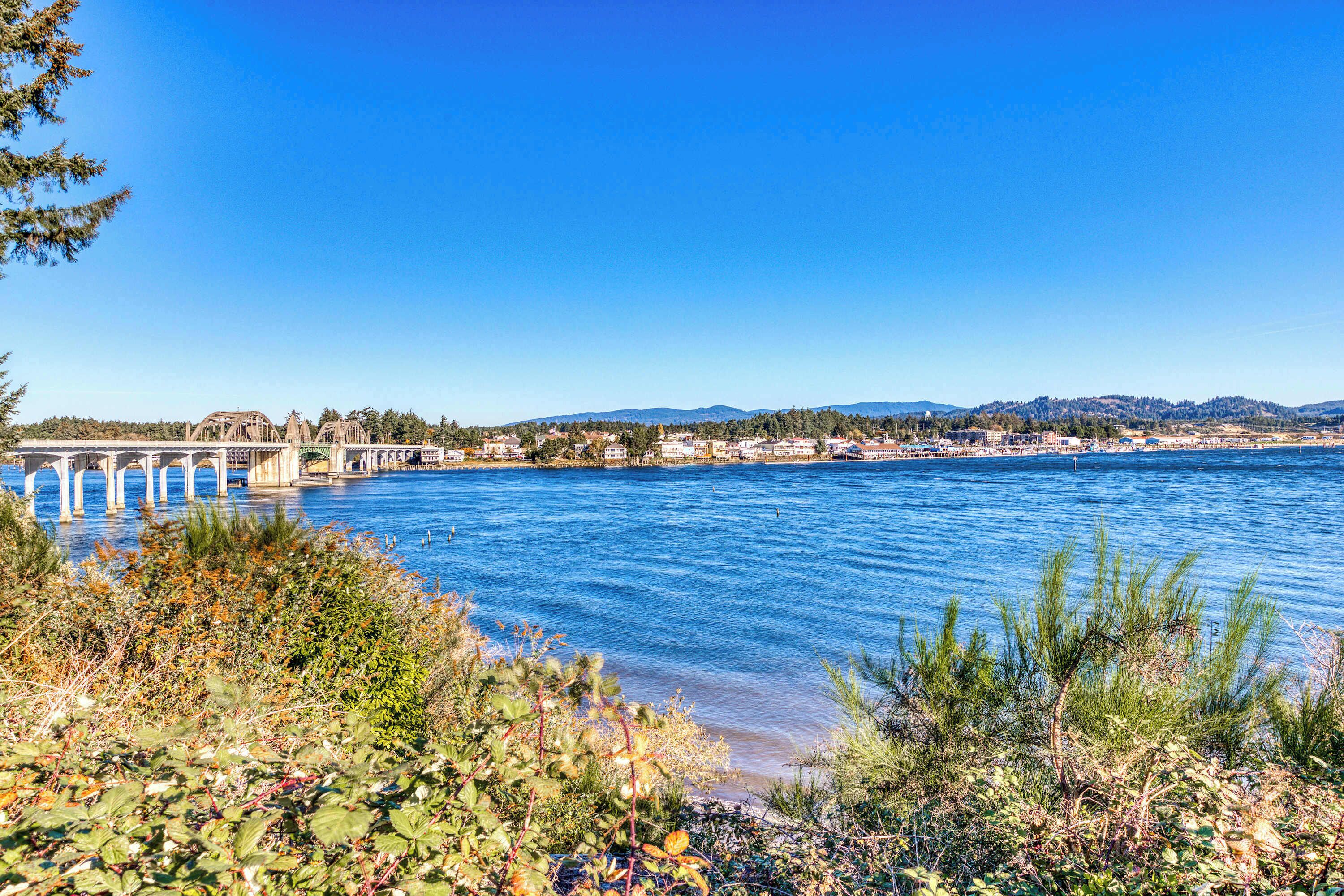A river with a bridge, greenery, and distant hills.
