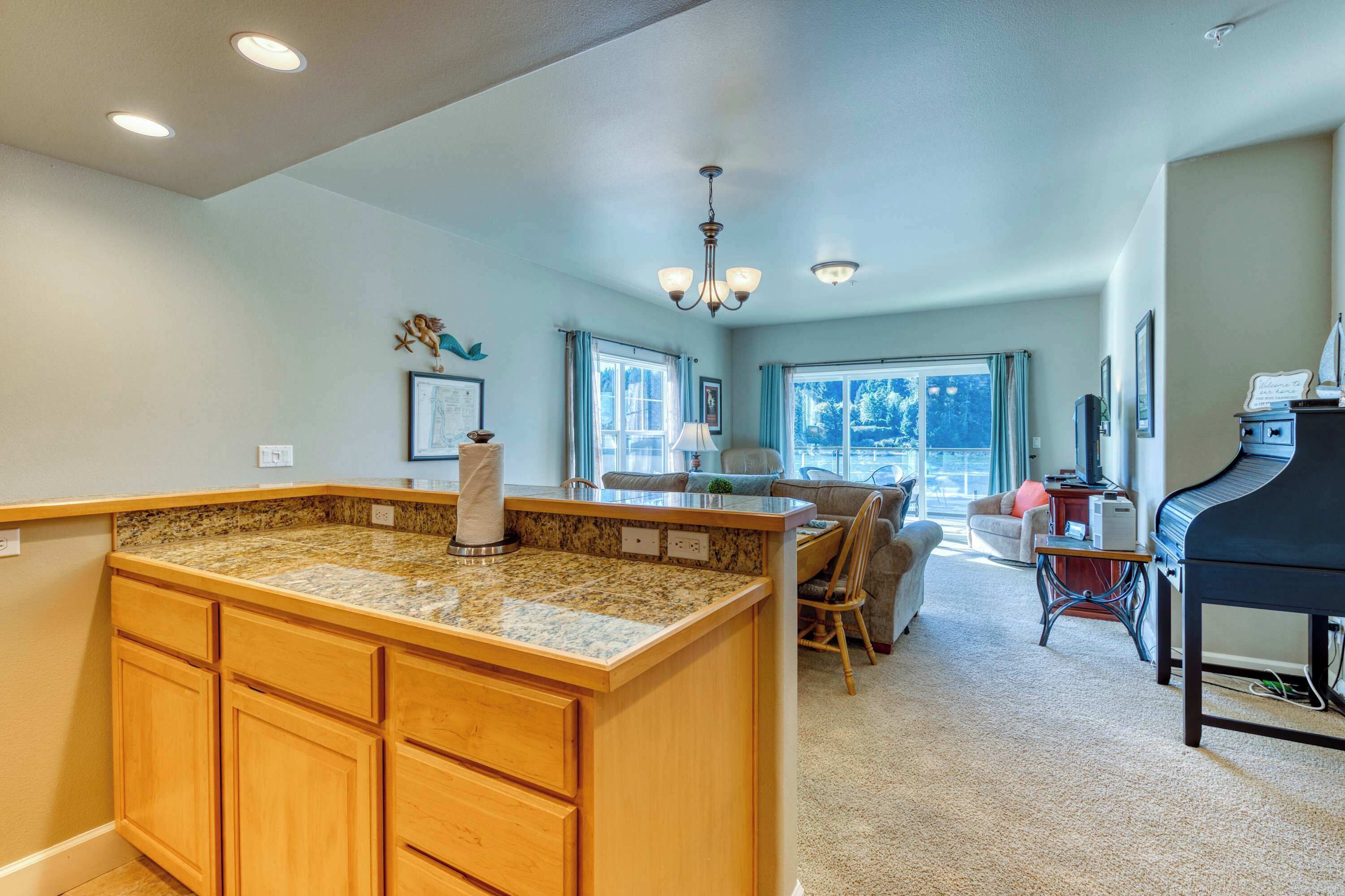 A kitchen with granite countertops, wooden cabinets, a dining area with a piano, and large windows.