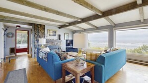 Een ruime woonkamer met een groot raam, een stenen muur en een blauwe bank.