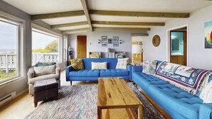 Een woonkamer met een blauwe bank, een houten bijzettafeltje en een kamerkleed met een patroon.