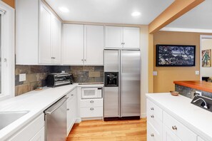 A modern kitchen with white cabinets, a stainless steel refrigerator, a microwave, and a toaster.