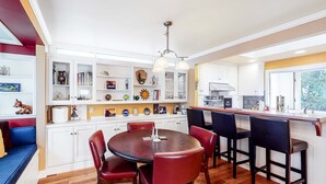 A kitchen with white cabinets, a dining table with chairs, and a built-in bar area.