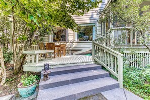 A wooden staircase leading to a porch with a table and chairs, surrounded by greenery. - Classic, Dog-Friendly Home with Free WiFi, a washer&dryer, & Enclosed Backyard (Eugene)