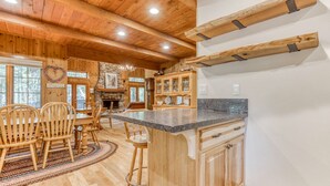 A wooden interior with a kitchen island, dining area, and bar stools. - Historic Waterfront Cabin with Hot Tub & Salmon River Access - Dog-Friendly (Welches)