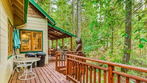 Una terraza de madera con una mesa y sillas, rodeada de un bosque.