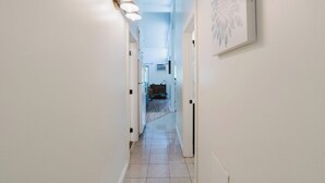 A hallway with white walls, a tiled floor, and a light fixture on the left. - Dog-Friendly Condo Steps from the Village with Balcony, WiFi & Gas Fireplace (Sunriver)