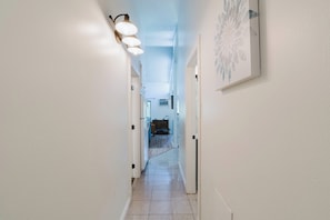 A hallway with white walls, a tiled floor, and a light fixture on the left. - Dog-Friendly Condo Steps from the Village with Balcony, WiFi & Gas Fireplace (Sunriver)