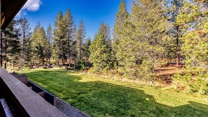 A view of a forested area with a clear sky, a grassy field, and a wooden structure. - Dog-Friendly Condo Steps from the Village with Balcony, WiFi & Gas Fireplace (Sunriver)