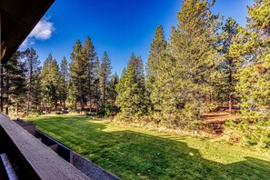 A view of a forested area with a clear sky, a grassy field, and a wooden structure. - Dog-Friendly Condo Steps from the Village with Balcony, WiFi & Gas Fireplace (Sunriver)