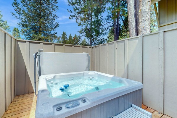 Un bain à remous installé à l’extérieur, avec une terrasse en bois et une clôture en bois.
