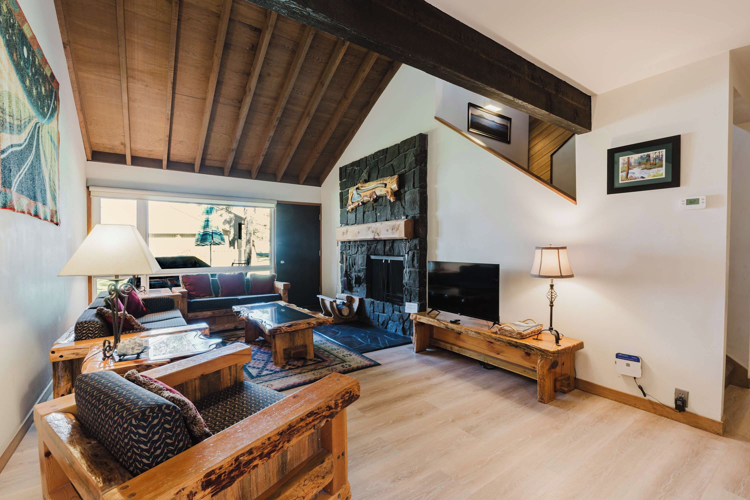 A spacious living room with a high ceiling, a stone fireplace, a television, and a cozy seating area with a sofa and coffee table.