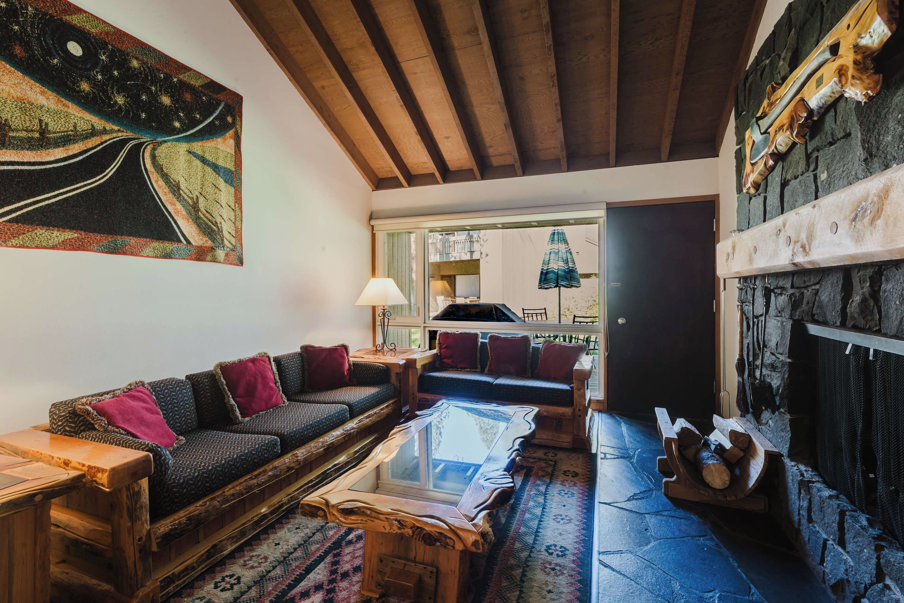 Un salon chaleureux avec un plafond en bois, une cheminée, un canapé et un grand tableau abstrait.
