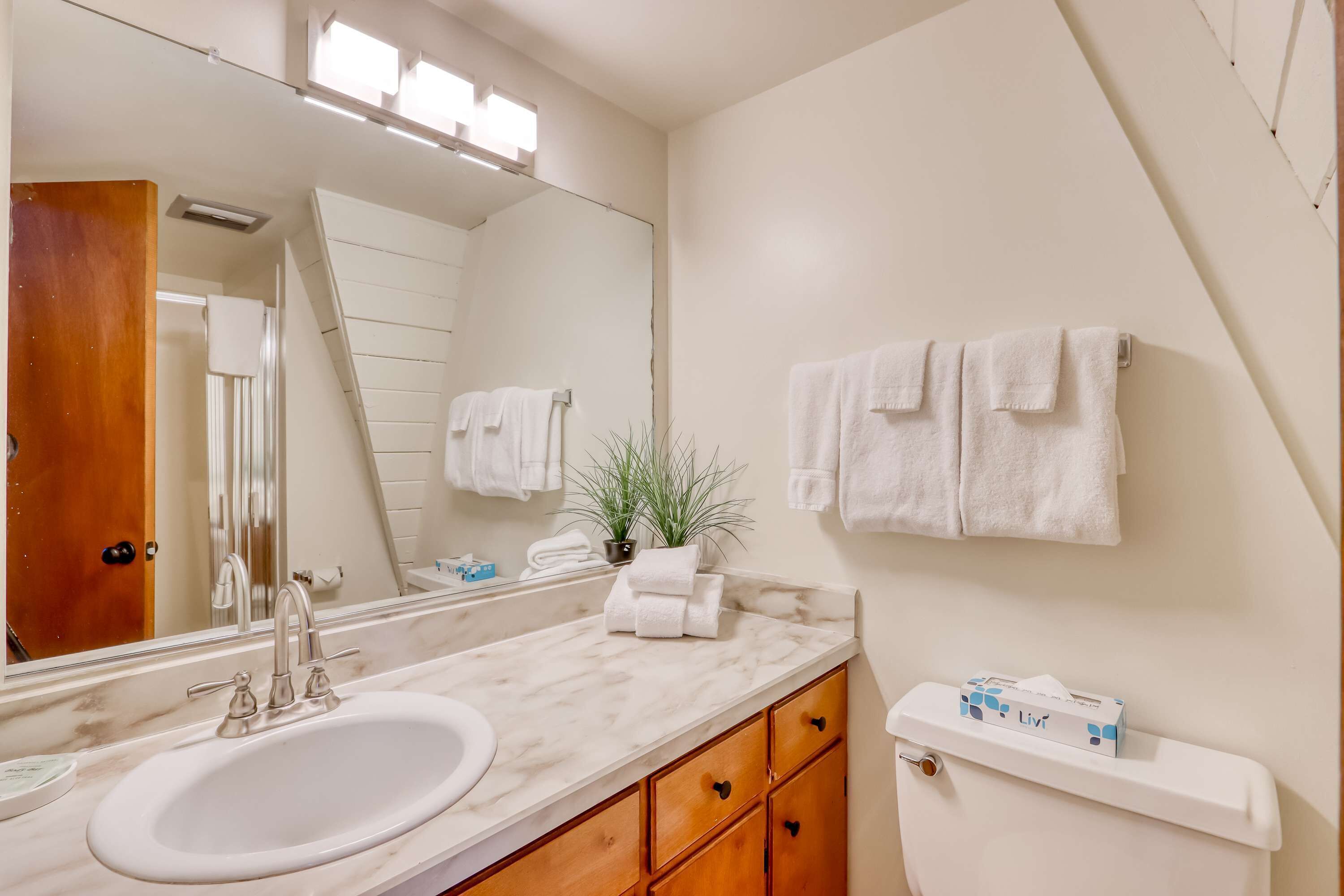 A bathroom with a sink, mirror, towel rack, and a toilet with a tissue box.