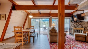 A cozy, wooden interior with a dining area, sofa, and TV. - Cozy Family Cabin with Hot Tub, Bikes, Dog-Friendly, Free WIFI with SHARC passes (Sunriver)