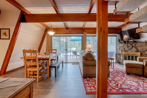 A cozy, wooden interior with a dining area, sofa, and TV. - Cozy Family Cabin with Hot Tub, Bikes, Dog-Friendly, Free WIFI with SHARC passes (Sunriver)
