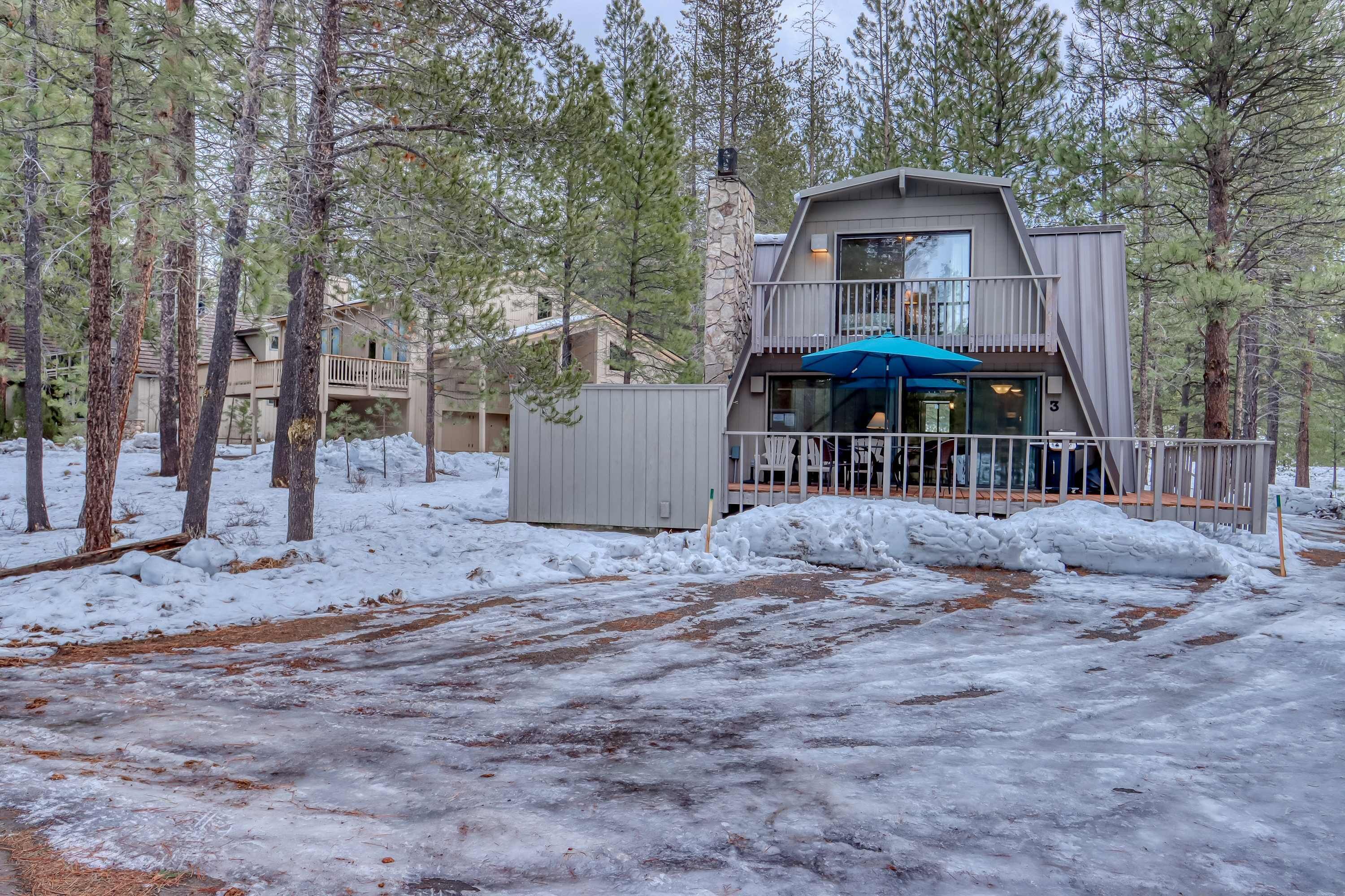 A cabin with a balcony, surrounded by trees and snow.