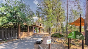 Een bordje van een natuurcentrum, een houten gebouw en een picknicktafel.