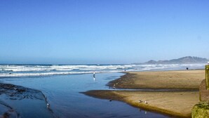Een strand met golven, een zandstrand en een berg in de verte.