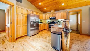 A kitchen with wooden cabinets, a refrigerator, a microwave, and a wooden island. - Dog-Friendly Sunriver Home with Fireplace, Deck & Central AC (Sunriver)