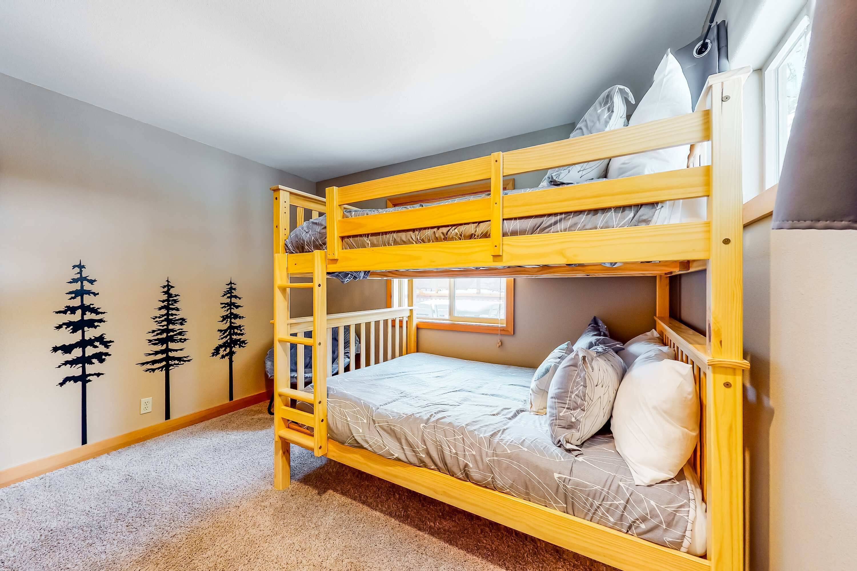 A bunk bed with a ladder, a window with curtains, and wall decorations.