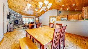 A spacious kitchen with wooden cabinets, a central island, and a stone fireplace. - Dog-Friendly Sunriver Home with Fireplace, Deck & Central AC (Sunriver)