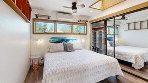 Ein Schlafzimmer mit Bett, Deckenventilator, Fenster und Spiegel.