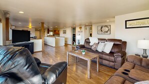 Een ruime woonkamer met een leren bank, een houten salontafel en een televisie.