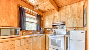 Una cucina in legno con forno a microonde, fornello e frigorifero.