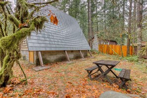Eine rustikale Holzhütte mit geneigtem Dach, einer Holzdiele und einem Picknicktisch.