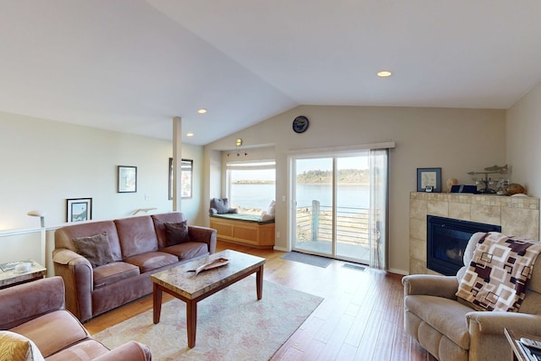 A living room with a sofa, a coffee table, a fireplace, and a view of the outdoors.