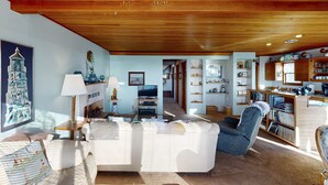 Ein Wohnzimmer mit einem weißen Sofa, einem blauen Sessel, einer Lampe und einem Fernseher.