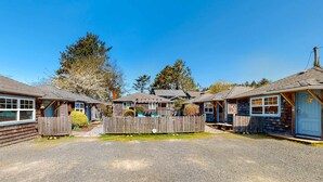 A row of cabins with a gravel driveway, wooden fences, and a clear blue sky. - Dog-Friendly Beach Condo with Free WiFi - Close to Beach (Cannon Beach)