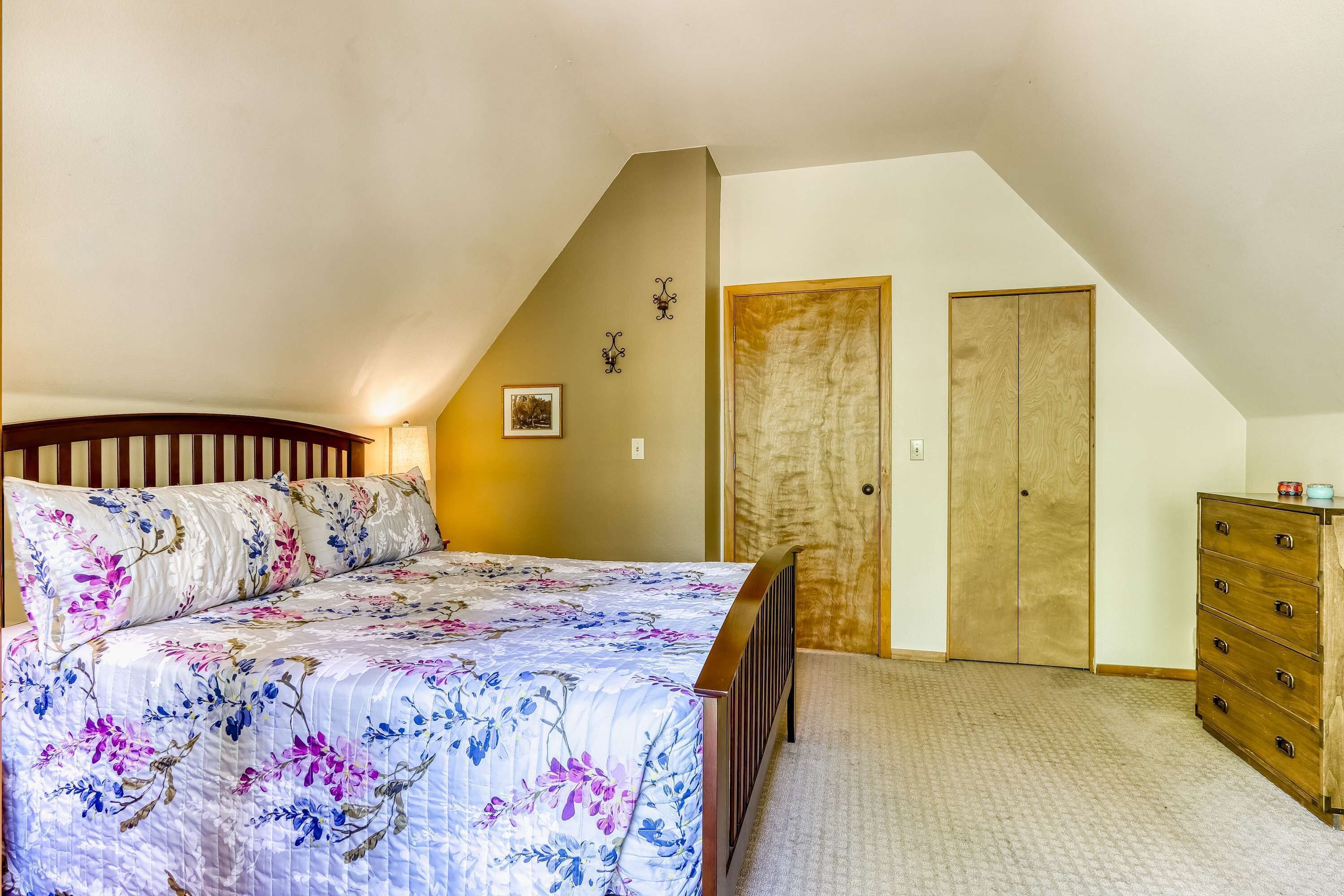 Ein Schlafzimmer mit Bett, Kommode und zwei Türen.