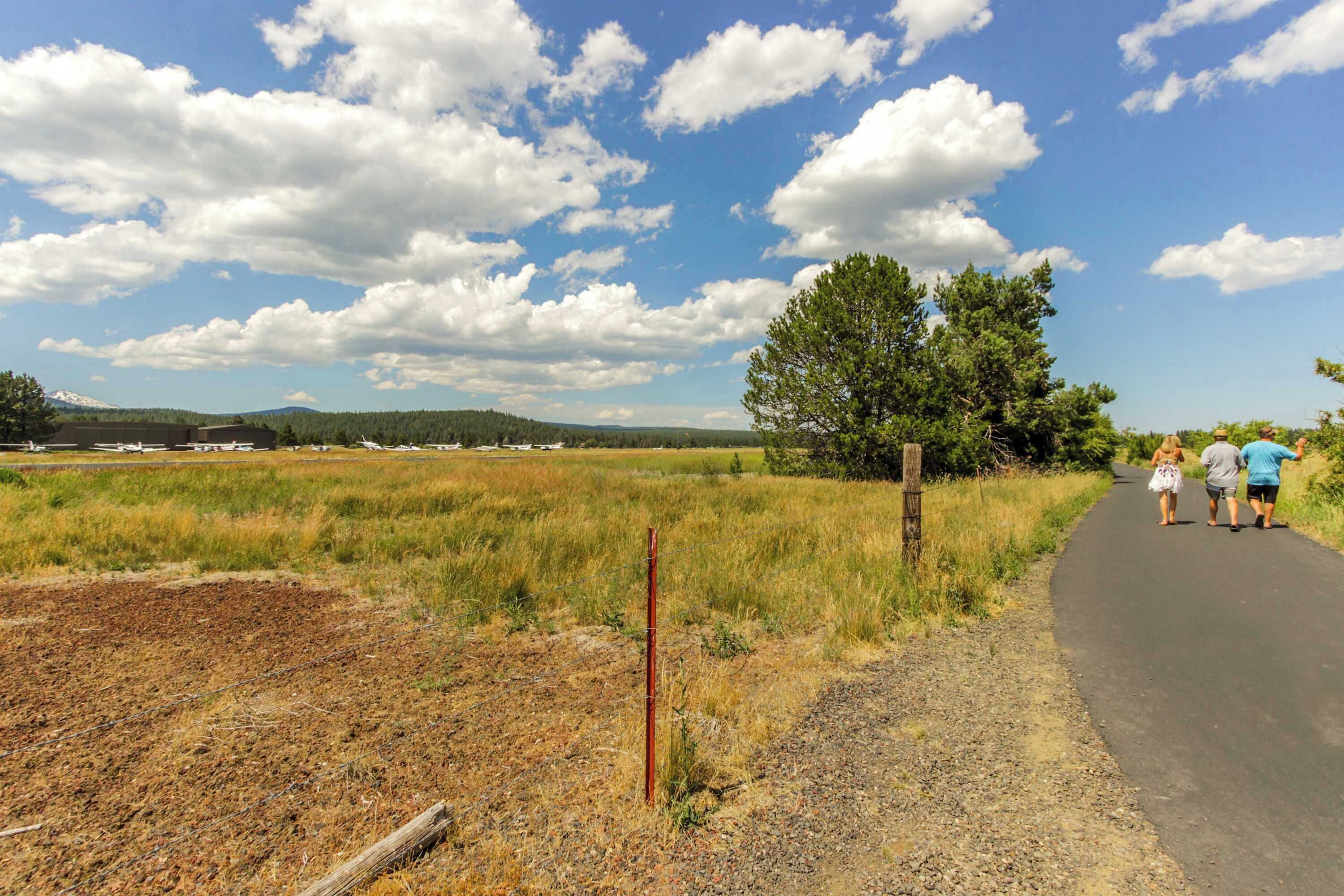 Un paysage rural avec un chemin pavé, des champs ouverts et un ciel dégagé.