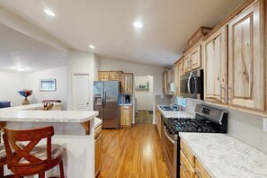 Une cuisine avec des meubles en bois, un réfrigérateur en acier inoxydable, un four à micro-ondes et une cuisinière.