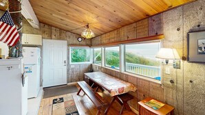 Un intérieur en bois avec une table, un banc et des fenêtres donnant sur un espace verdoyant.